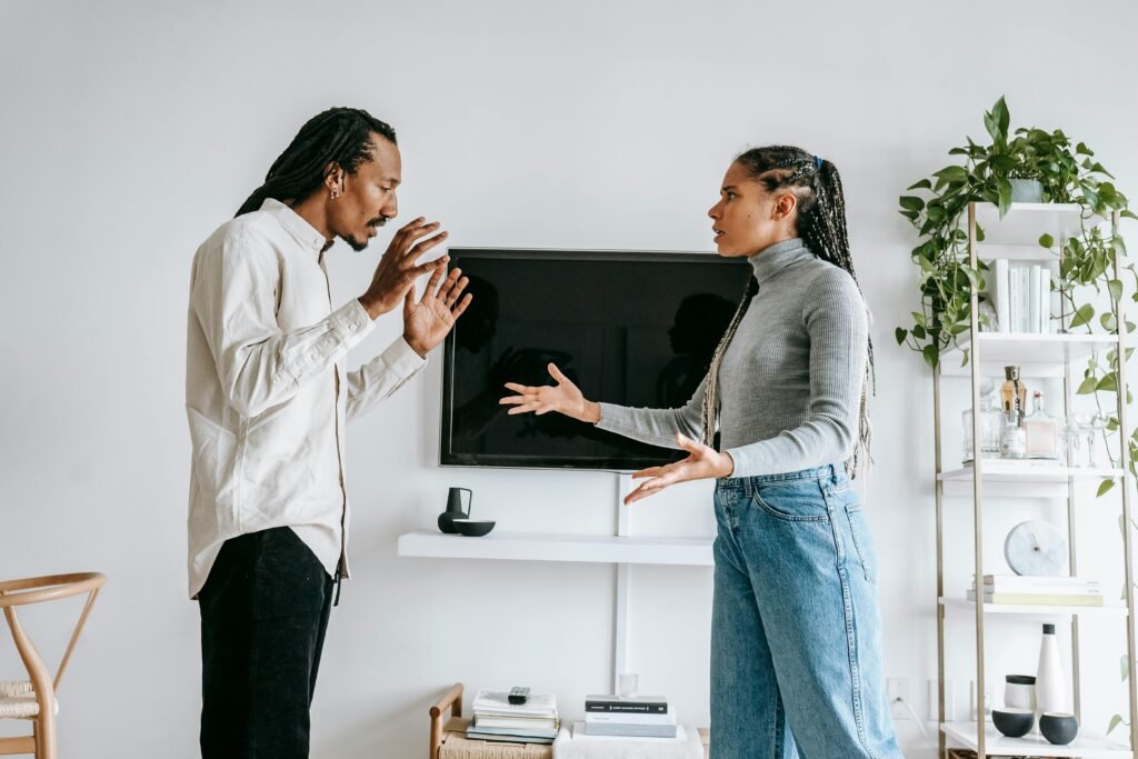 A young couple engaged in a tense argument in their modern living room setting.